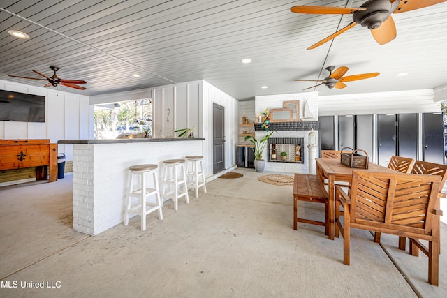 exterior space with a brick fireplace, ceiling fan, outdoor dining area, and exterior bar