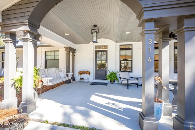 entrance to property with a porch and brick siding