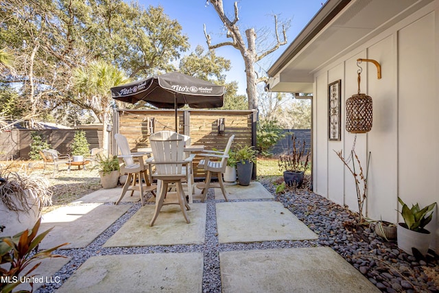 view of patio featuring outdoor dining area and fence