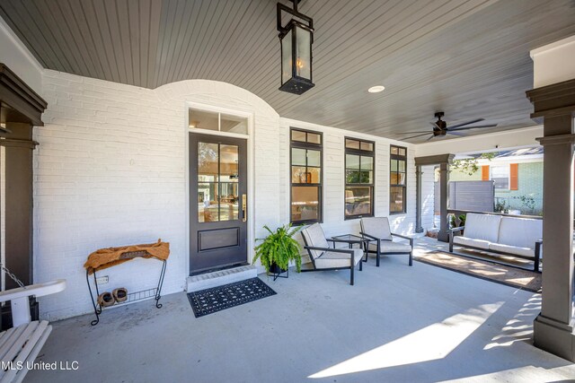 entrance to property featuring covered porch, ceiling fan, and brick siding