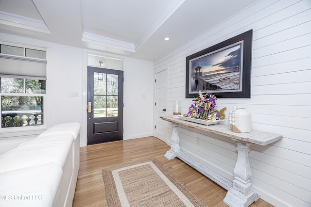 foyer entrance featuring crown molding, light wood finished floors, recessed lighting, a raised ceiling, and baseboards