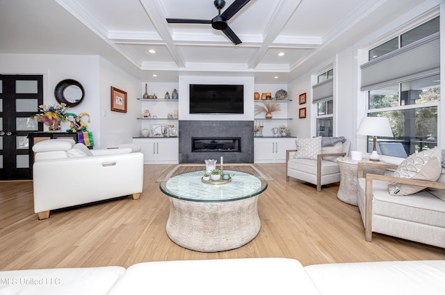 living room with light wood-type flooring, a glass covered fireplace, coffered ceiling, and beamed ceiling