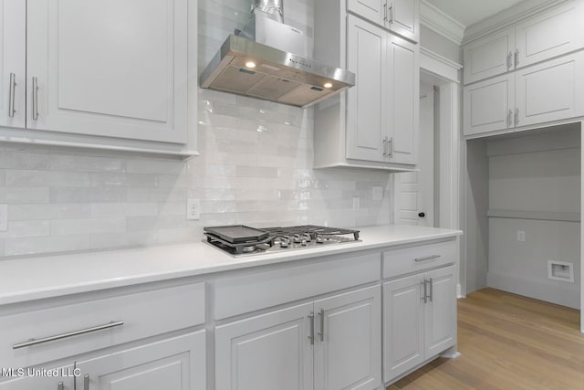 kitchen with stainless steel gas cooktop, light hardwood / wood-style floors, wall chimney exhaust hood, and white cabinets