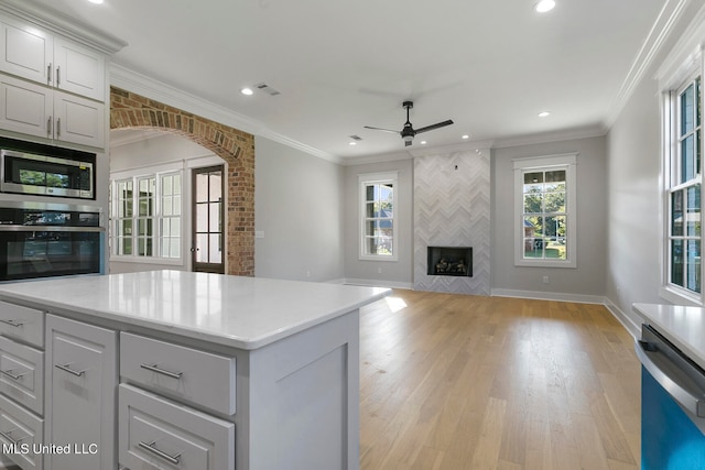 kitchen with crown molding, appliances with stainless steel finishes, light hardwood / wood-style flooring, and a kitchen island