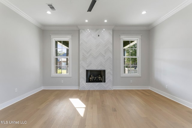 unfurnished living room featuring ornamental molding, plenty of natural light, and light wood-type flooring