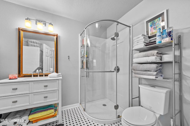 bathroom featuring a shower with door, vanity, a textured ceiling, and toilet