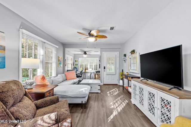 living room with hardwood / wood-style floors, ceiling fan, and a textured ceiling