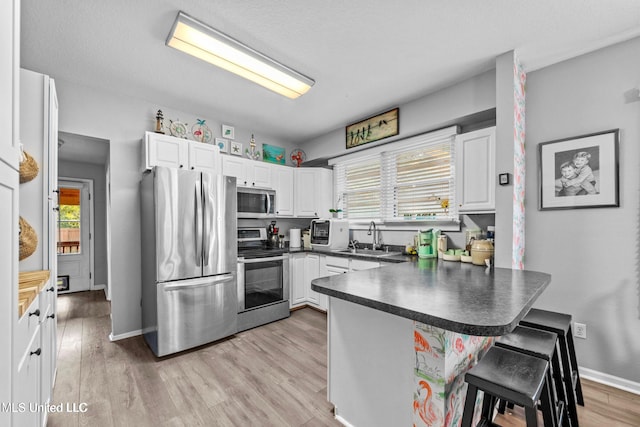 kitchen featuring appliances with stainless steel finishes, white cabinetry, a wealth of natural light, and a kitchen breakfast bar