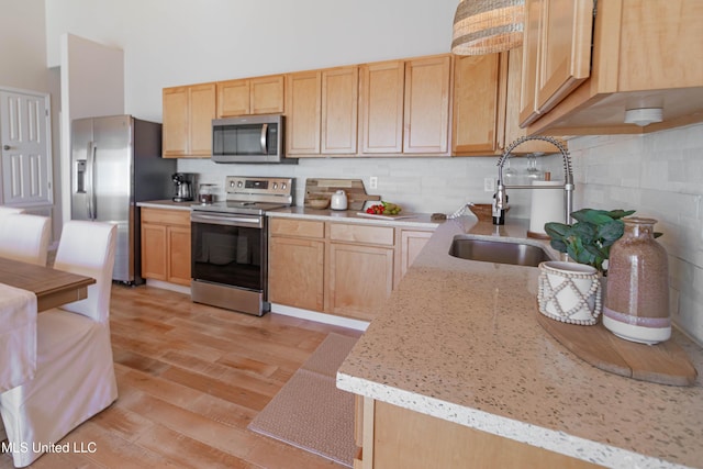 6717 Belle Fontaine Dr, Ocean Springs, MS 39564 - kitchen with a sink, light stone counters, light wood-style floors, light brown cabinets, and stainless steel appliances