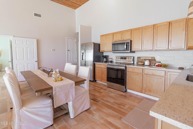 6717 Belle Fontaine Dr, Ocean Springs, MS 39564 - kitchen featuring light brown cabinetry, appliances with stainless steel finishes, and high vaulted ceiling