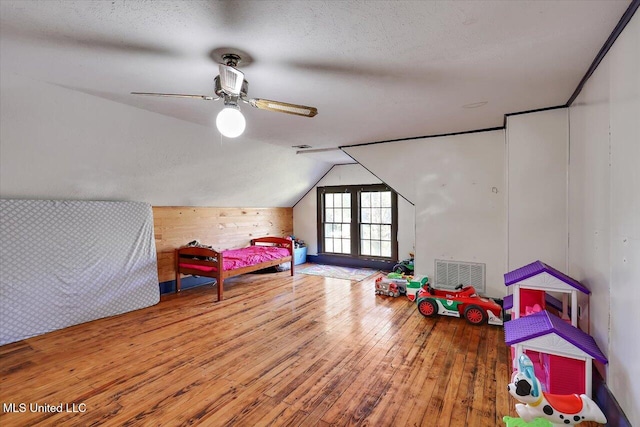 bedroom with lofted ceiling, ceiling fan, wood-type flooring, and a textured ceiling