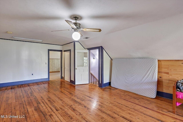 additional living space with ceiling fan, wood-type flooring, a textured ceiling, and vaulted ceiling