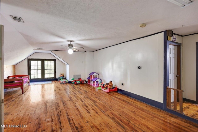 playroom featuring hardwood / wood-style floors, a textured ceiling, vaulted ceiling, and ceiling fan