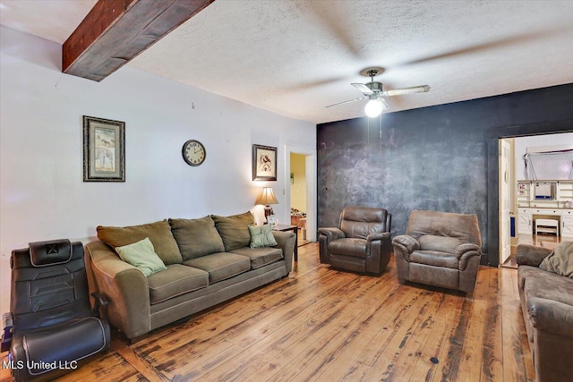 living room featuring ceiling fan, wood-type flooring, and a textured ceiling