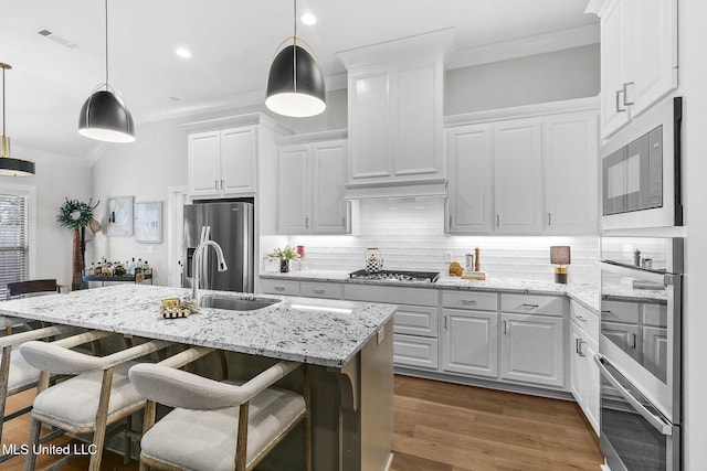 kitchen with pendant lighting, white cabinetry, a kitchen island with sink, and appliances with stainless steel finishes