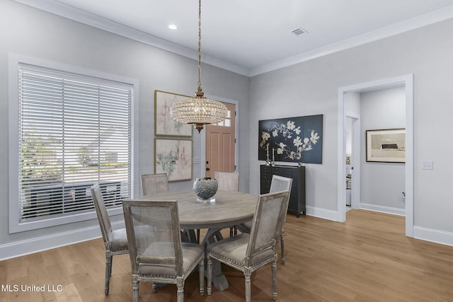 dining area with hardwood / wood-style floors, crown molding, and a notable chandelier