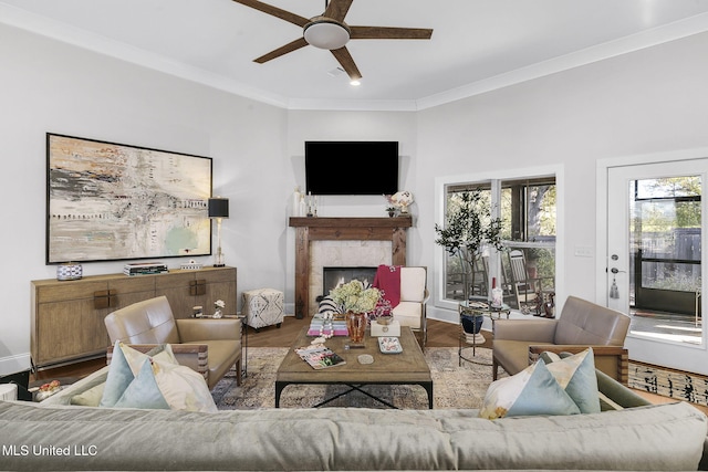 living room with ceiling fan, a fireplace, ornamental molding, and hardwood / wood-style flooring