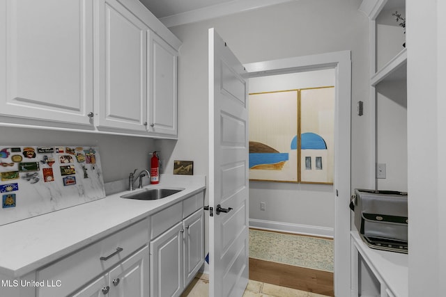 kitchen with white refrigerator, white cabinetry, and sink