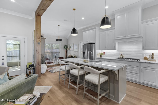 kitchen featuring a kitchen breakfast bar, white cabinets, an island with sink, and stainless steel appliances