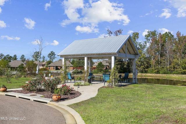 view of property's community with a gazebo, a water view, and a yard