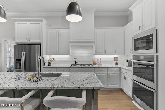 kitchen with sink, hanging light fixtures, a breakfast bar area, white cabinets, and appliances with stainless steel finishes