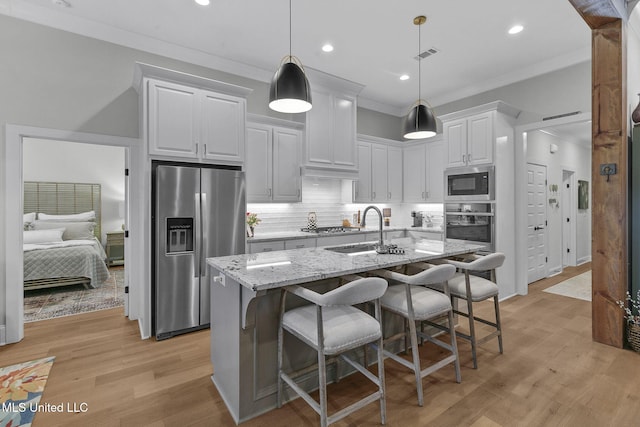 kitchen with pendant lighting, stainless steel appliances, white cabinetry, and light stone counters