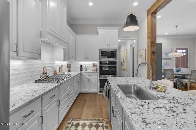 kitchen featuring white cabinets, decorative backsplash, decorative light fixtures, and sink