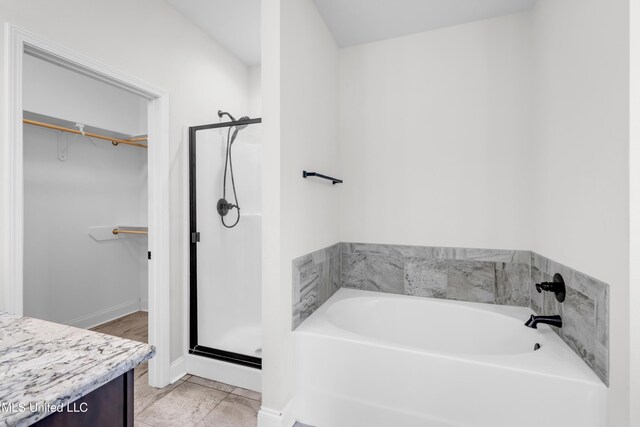 832 Reunion Place Cir, Biloxi, MS 39532 - bathroom with a bath, a walk in closet, a stall shower, vanity, and baseboards