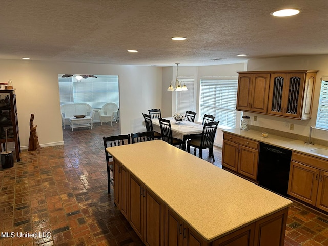 kitchen with black dishwasher, hanging light fixtures, a kitchen island, a breakfast bar, and a notable chandelier