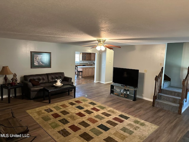 living room with dark hardwood / wood-style floors, a textured ceiling, and ceiling fan