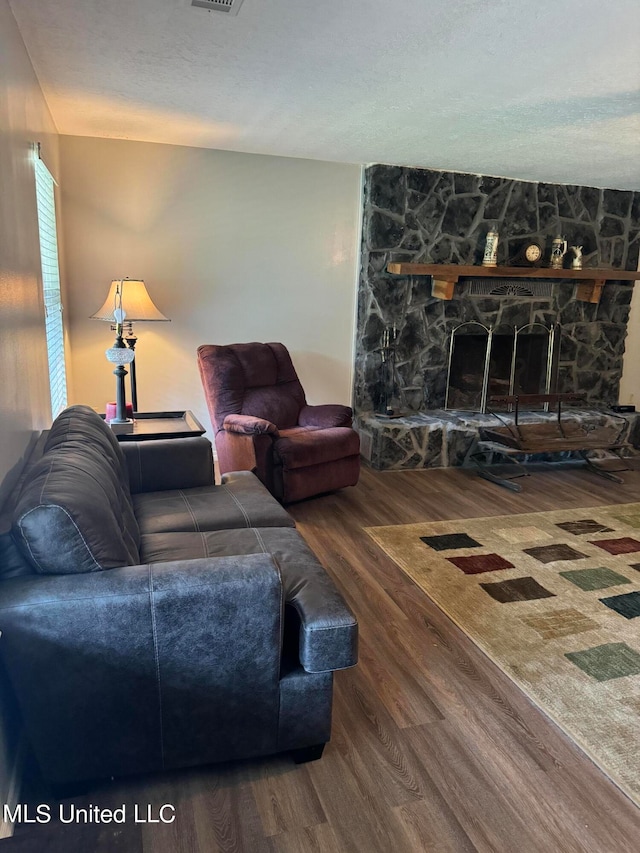 living room featuring a stone fireplace and hardwood / wood-style flooring