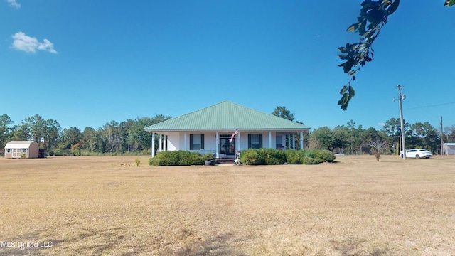 view of front of home with covered porch, a front yard, and an outdoor structure