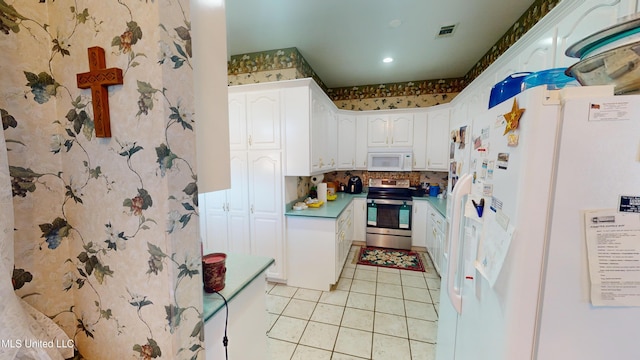 4385 Stringfellow Rd, Lucedale, MS 39452 - kitchen with white cabinets, light tile patterned floors, visible vents, white appliances, and wallpapered walls