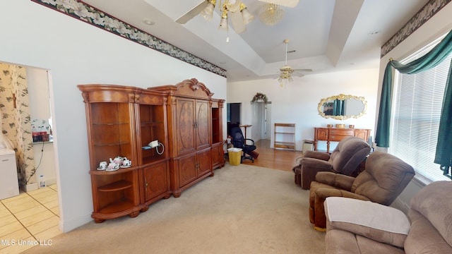 living room with ceiling fan, light carpet, a tray ceiling, and plenty of natural light