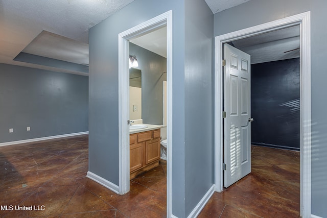 corridor with a textured ceiling, dark tile patterned floors, and sink