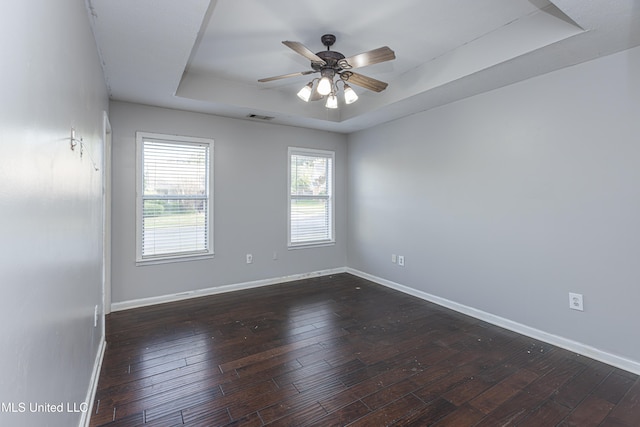 unfurnished room with dark hardwood / wood-style flooring, ceiling fan, and a raised ceiling