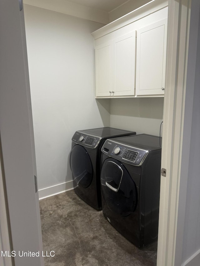 washroom with baseboards, cabinet space, and washer and dryer