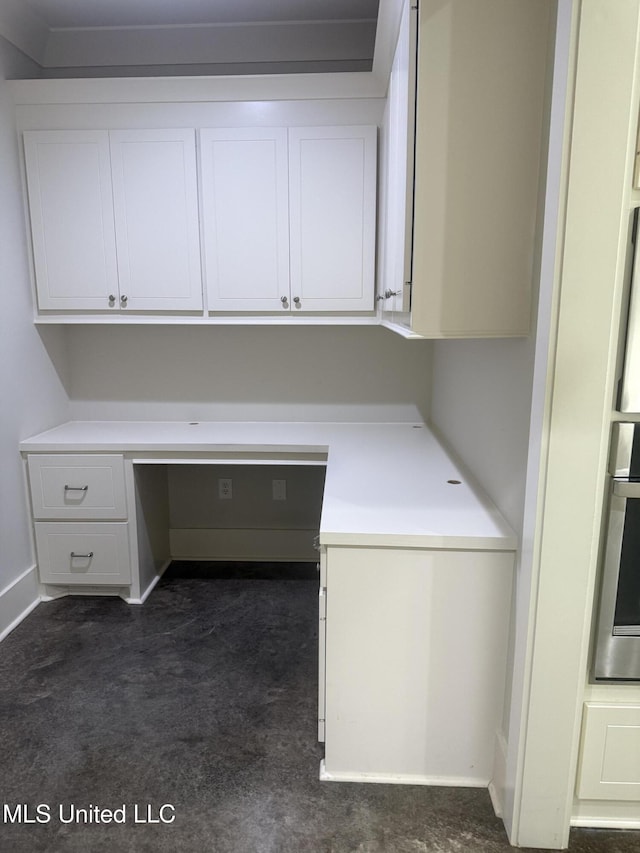 laundry area with baseboards and dark carpet