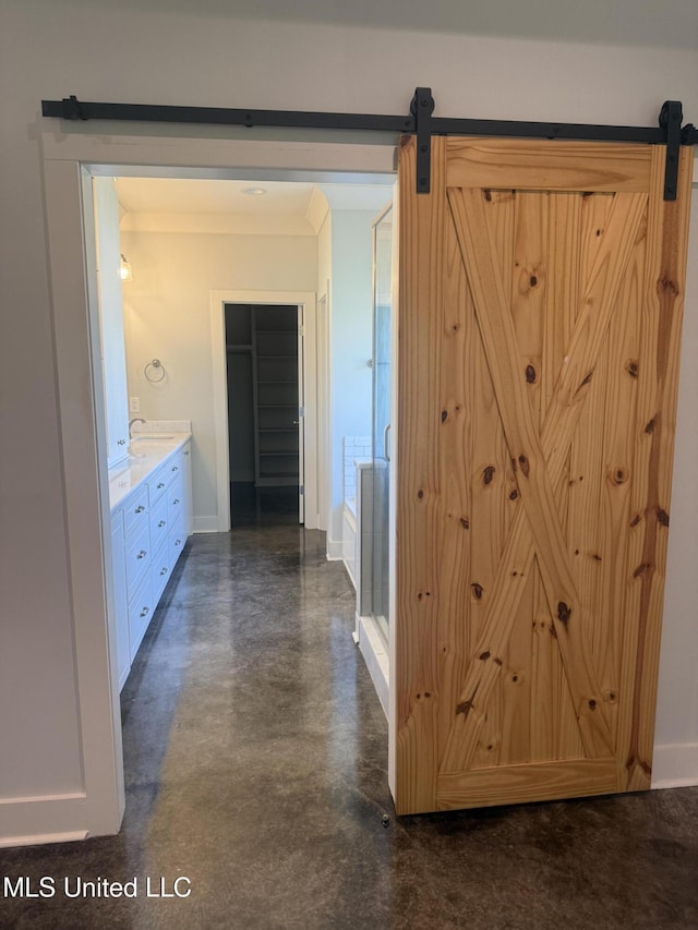hall with baseboards, a barn door, and concrete floors