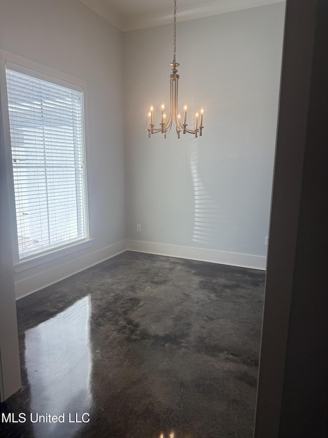 spare room featuring baseboards, concrete flooring, and a notable chandelier