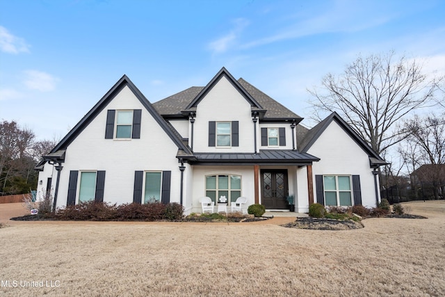 view of front of property featuring roof with shingles, brick siding, a front yard, a standing seam roof, and metal roof