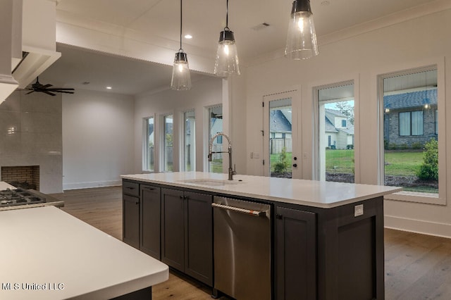 kitchen featuring dark wood-type flooring, an island with sink, ornamental molding, pendant lighting, and ceiling fan