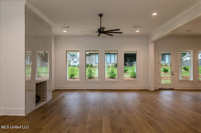 unfurnished living room featuring a fireplace, ceiling fan, plenty of natural light, and dark hardwood / wood-style flooring