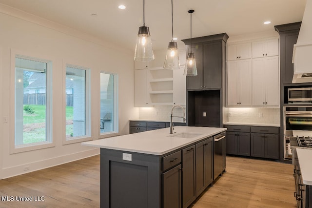 kitchen with light hardwood / wood-style floors, decorative backsplash, a kitchen island with sink, and sink