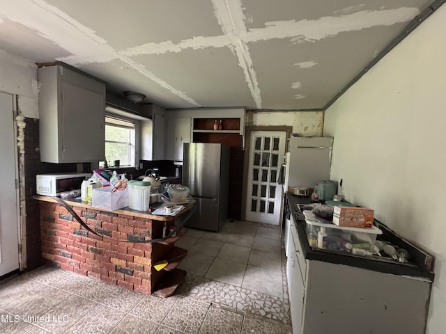 5418 Elder St, Moss Point, MS 39563 - kitchen with freestanding refrigerator, white microwave, open shelves, and light tile patterned floors