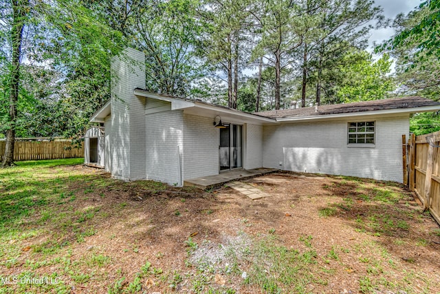 204 Turtle Creek Dr, Brandon, MS 39047 - rear view of house with a fenced backyard, brick siding, a chimney, and view of wooded area