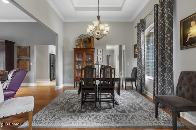 dining room with ornamental molding, hardwood / wood-style floors, a chandelier, and a tray ceiling