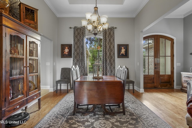 dining area featuring a healthy amount of sunlight, hardwood / wood-style floors, an inviting chandelier, and french doors