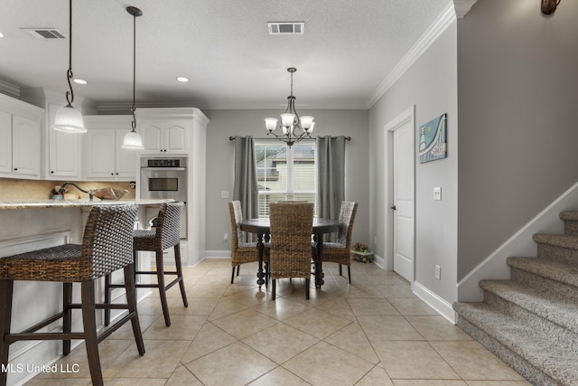 dining space featuring light tile patterned flooring, ornamental molding, a textured ceiling, and a notable chandelier