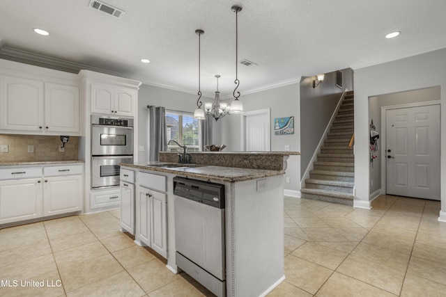 kitchen with stainless steel appliances, an island with sink, sink, and white cabinets